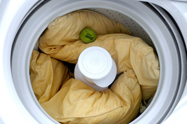 Pillows in washing machine with a tennis ball